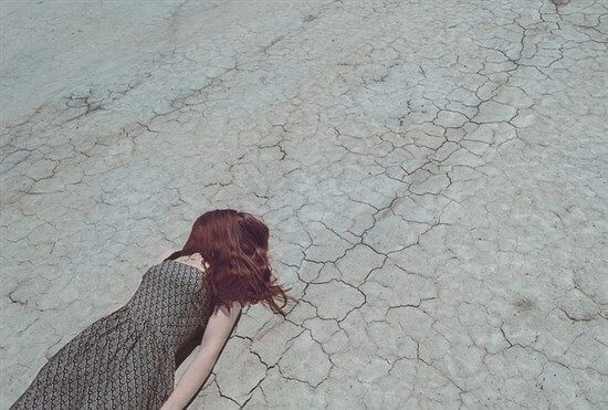 カラカラの地面に倒れる女性